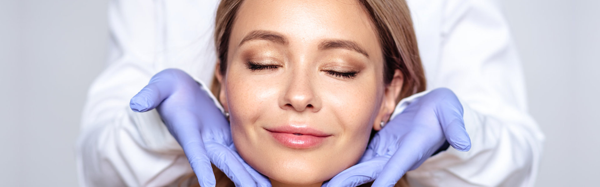 Close up portrait of young blonde woman with cosmetologyst hands in a gloves