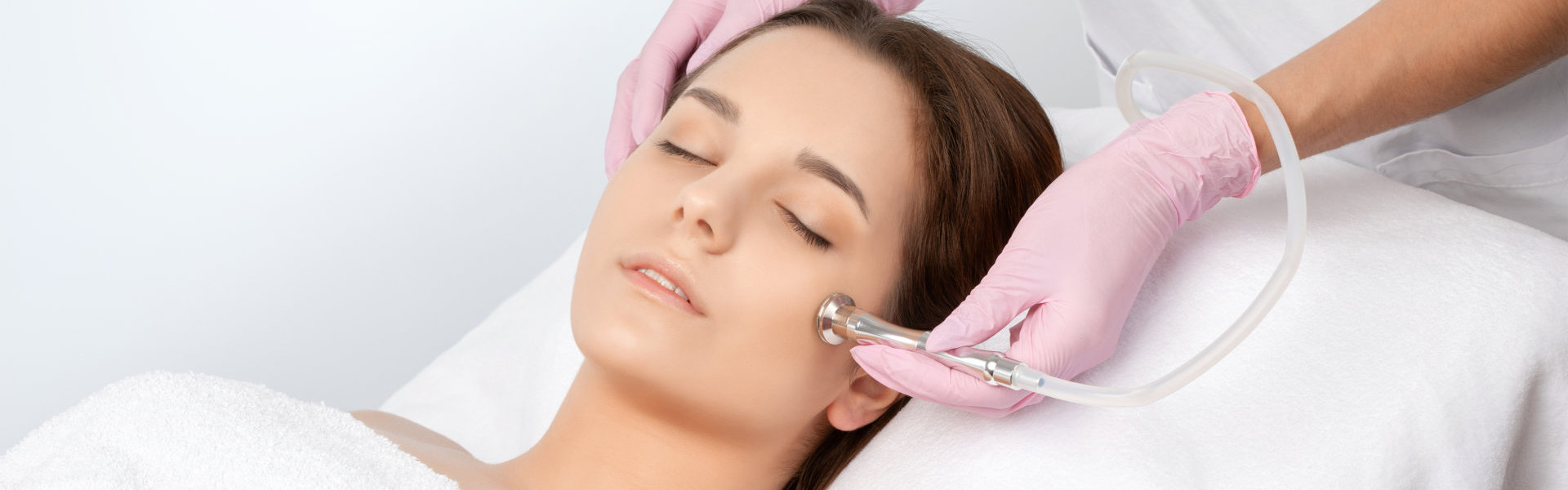 The cosmetologist makes the procedure Microdermabrasion of the face skin of a beautiful girl in a beauty salon